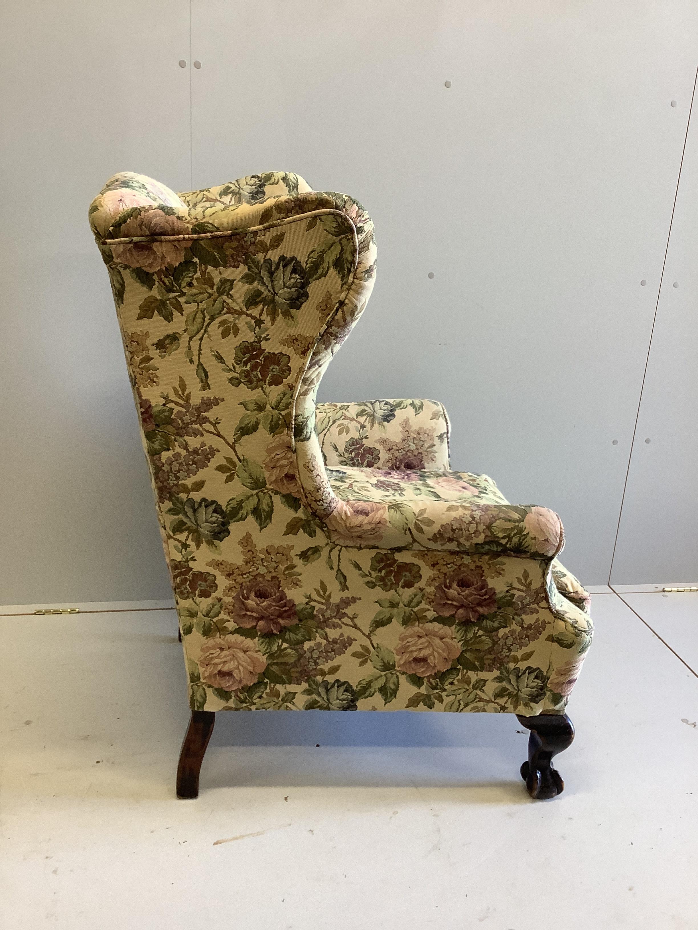 An early 20th century upholstered wing armchair on claw and ball feet, width 80cm, depth 76cm, height 110cm